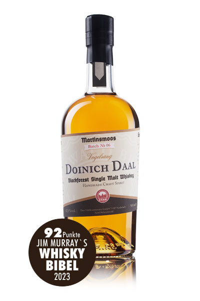 Das Bild zeigt eine Flasche Doinich Daal Blackforest Single Malt Whiskey, die von Jim Murrays Whisky Bibel 2023 mit 92 Punkten bewertet wurde.
Das Bild zeigt eine einzelne Flasche Doinich Daal Blackforest Single Malt Whiskey aus der Brennerei Martinsmoos, Charge Nr. 06, Vogelsang. Die Flasche ist aus klarem Glas und enthält eine goldgelbe Flüssigkeit. Sie hat einen schwarzen Verschluss und ein Etikett mit beige-braunen Farbtönen. Das Etikett zeigt den Namen der Marke und des Whiskys, den Hinweis auf Single