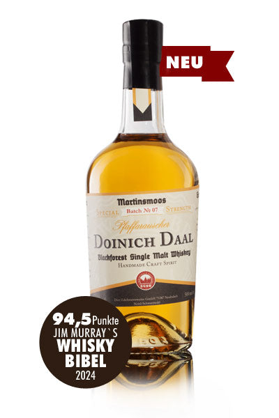Das Bild zeigt eine Flasche Doinich Daal Blackforest Single Malt Whiskey, die von Jim Murrays Whisky Bibel 2024 mit 94,5 Punkten bewertet wurde.
Das Bild zeigt eine einzelne Flasche Doinich Daal Blackforest Single Malt Whiskey aus der Brennerei Martinsmoos, Charge Nr. 07, Pfaffenrauscher. Die Flasche ist aus klarem Glas und enthält eine goldgelbe Flüssigkeit. Das Etikett zeigt den Namen der Marke und des Whiskys, den Hinweis auf Single Malt Whiskey aus dem Schwarzwald, sowie "Handmade Craft Spirit". Im unte