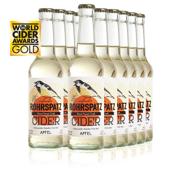Das Bild zeigt meherere Flasche Rohrspatz Apfel-Cider, die mit einer Goldmedaille der World Cider Awards ausgezeichnet wurde.
Das Bild zeigt mehrere Flaschne Rohrspatz Apfel Cider im Vordergrund, auf weißem Hintergrund. Die Flaschen sind aus Glas, klar und zylindrisch geformt mit einem leicht konischen Hals. Sie ist bis zum Hals mit einer hellgelben Flüssigkeit gefüllt. Das Etikett ist weiß mit einem orangefarbenen Kreis im Hintergrund, auf dem ein stilisierter, singender Vogel abgebildet ist. Der Name „RO